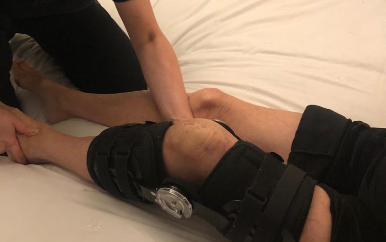 A person receiving treatment on their knee, wearing a knee brace.